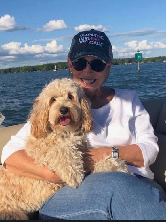 A woman and her Australian Labradoodle enjoying a beautiful sunny day on a boat.