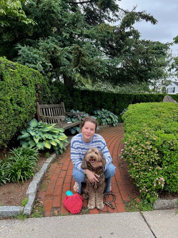A young woman with her Australian Labradoodle outside at a park together.